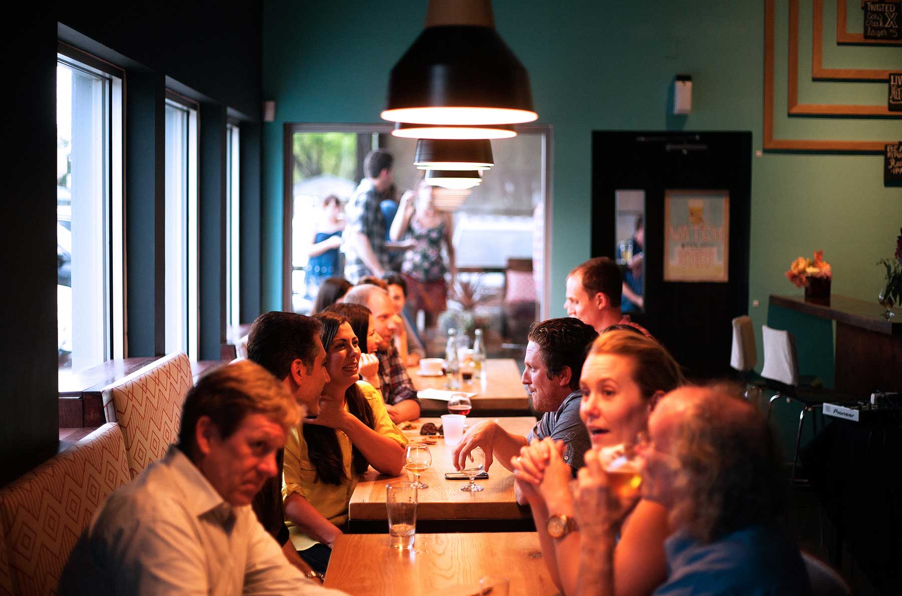 People sitting and talking over beers at several restaurant tables