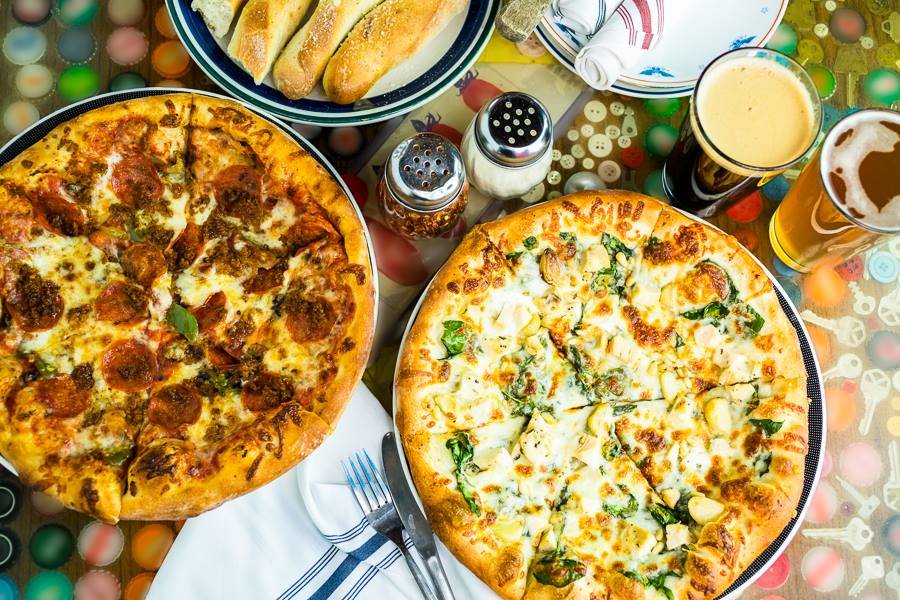 Deep dish pizzas, beer, and bread on a table