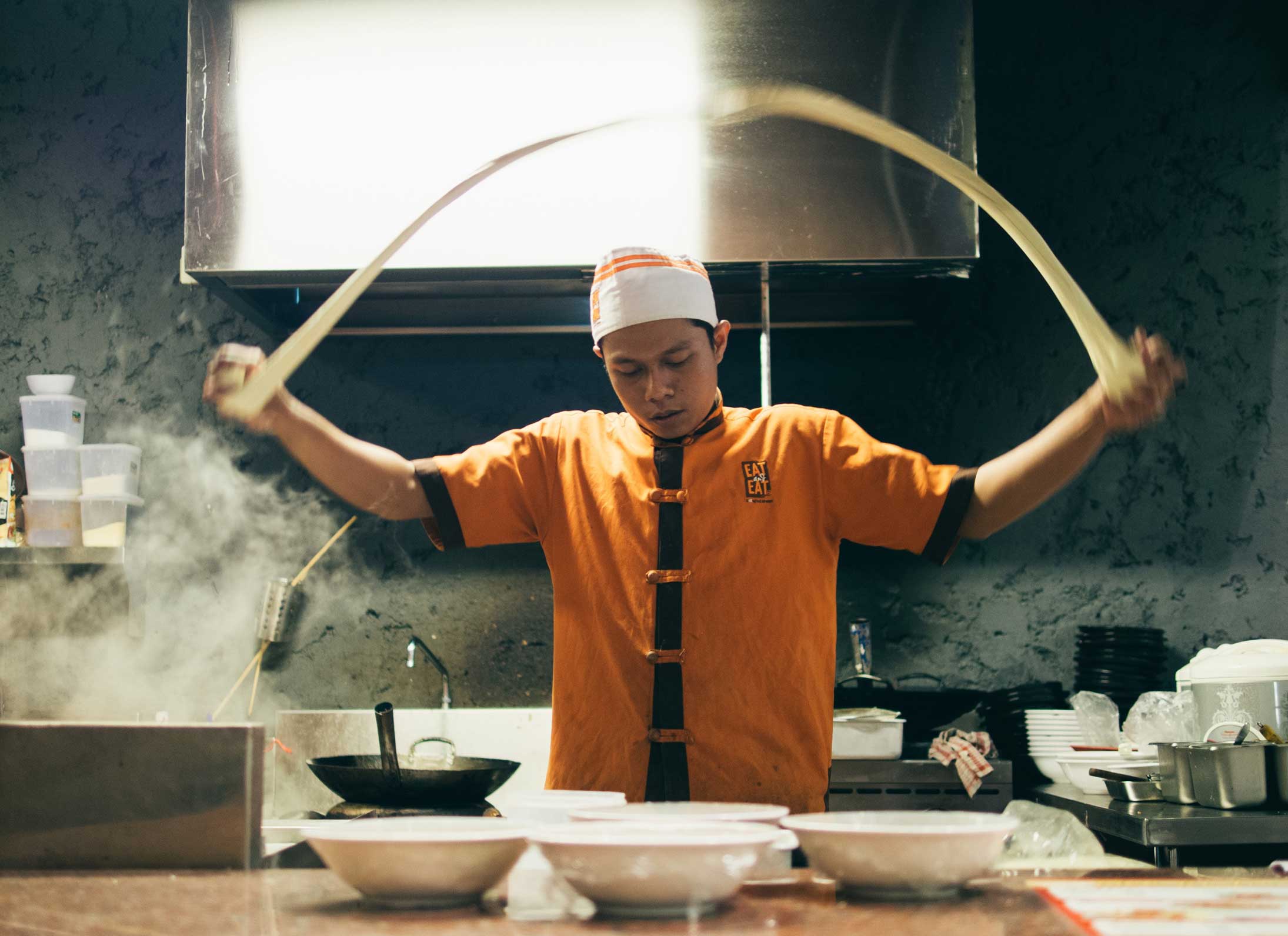 A chef stretching dough in a kitchen