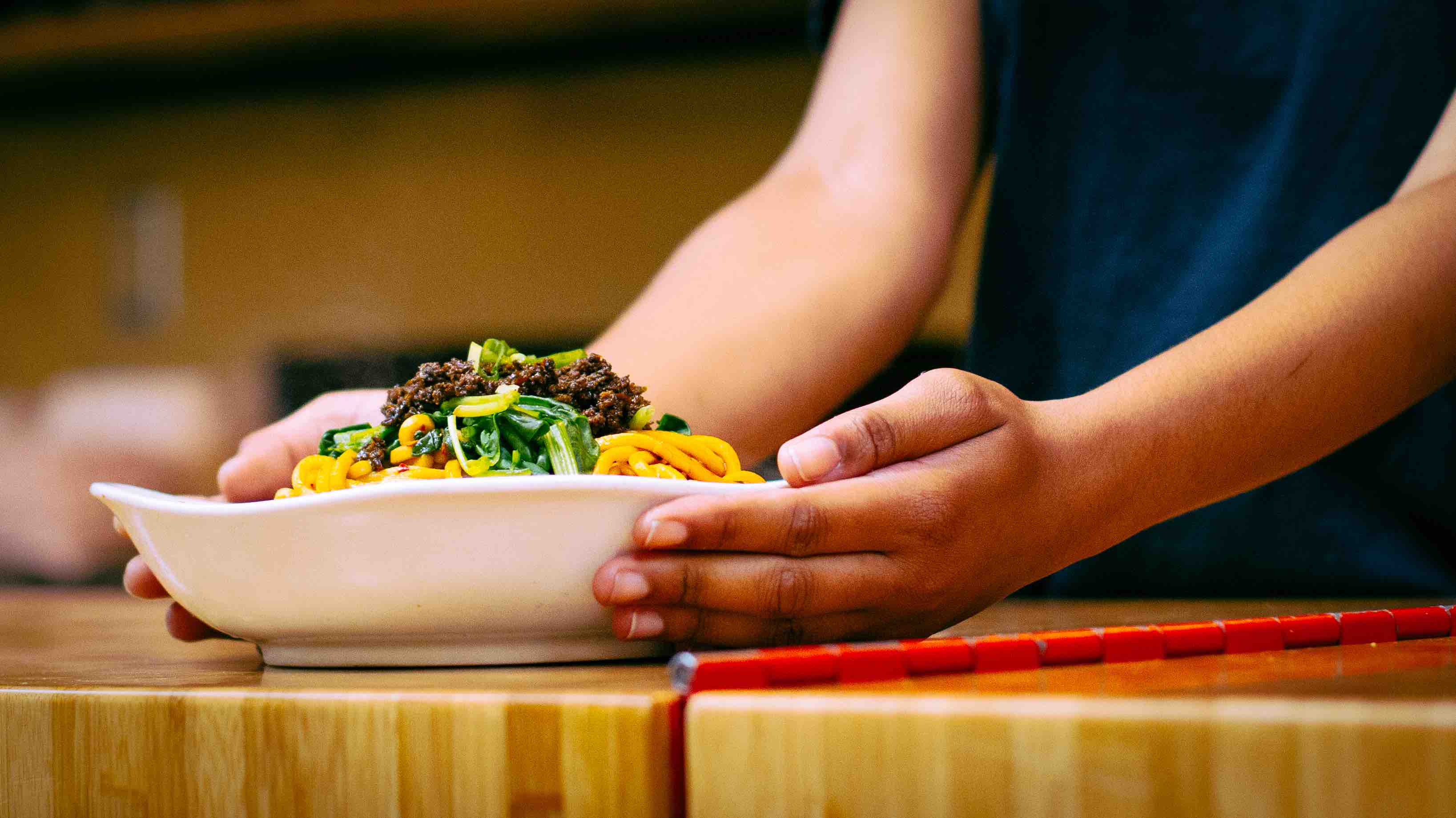 Hands serving up Gu's Dumplings