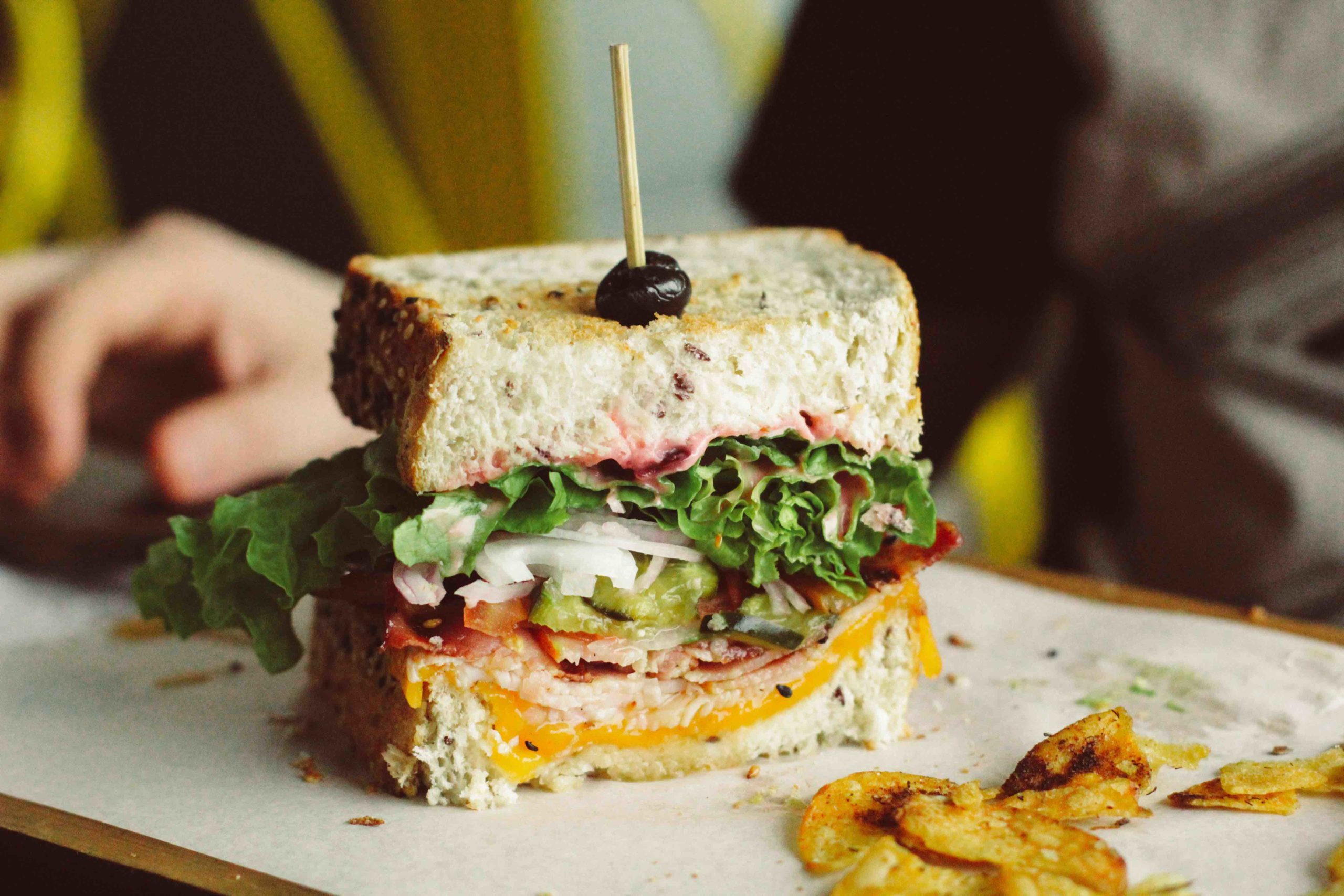 Stacked sandwich on a board with chips