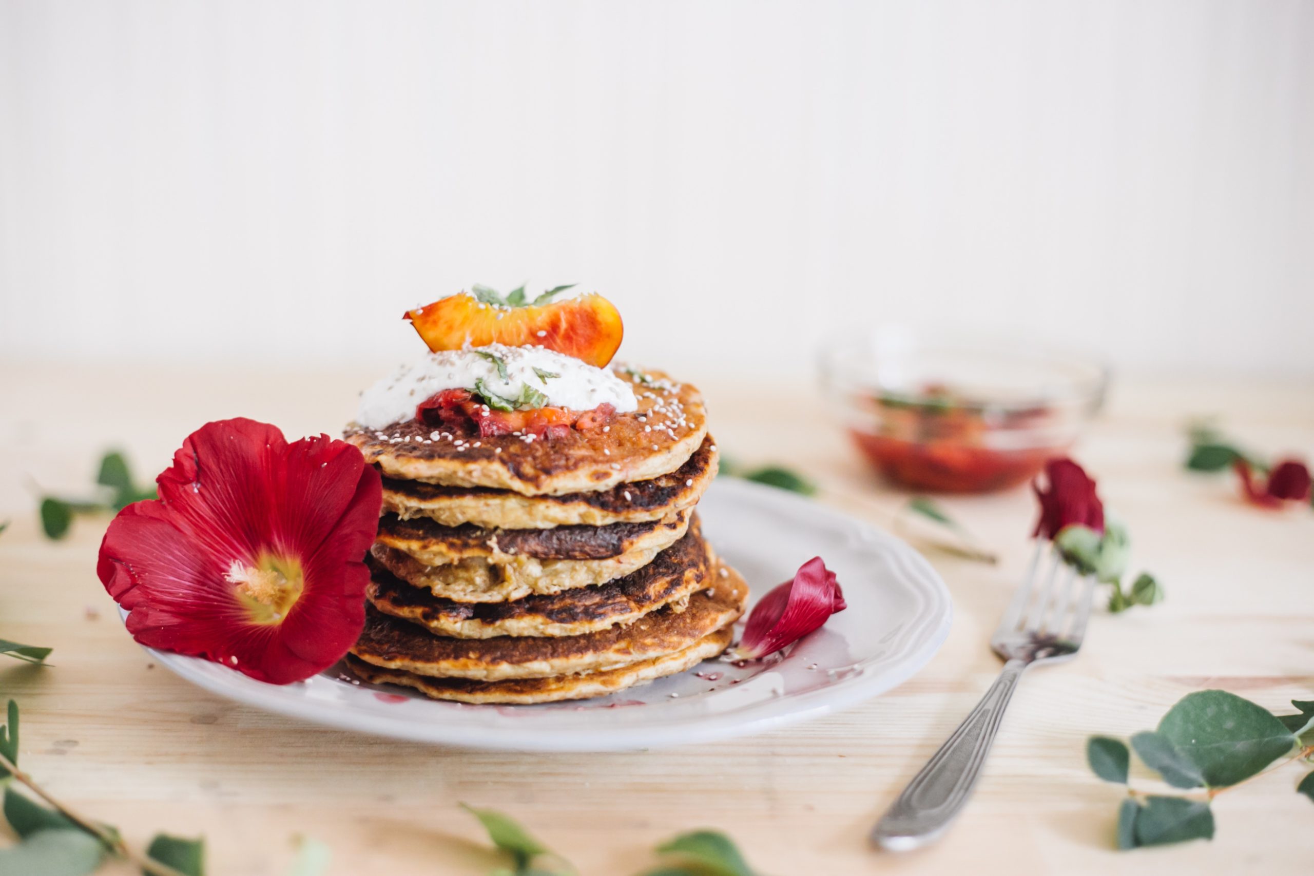 Stack of pancakes with toppings and flowers around it