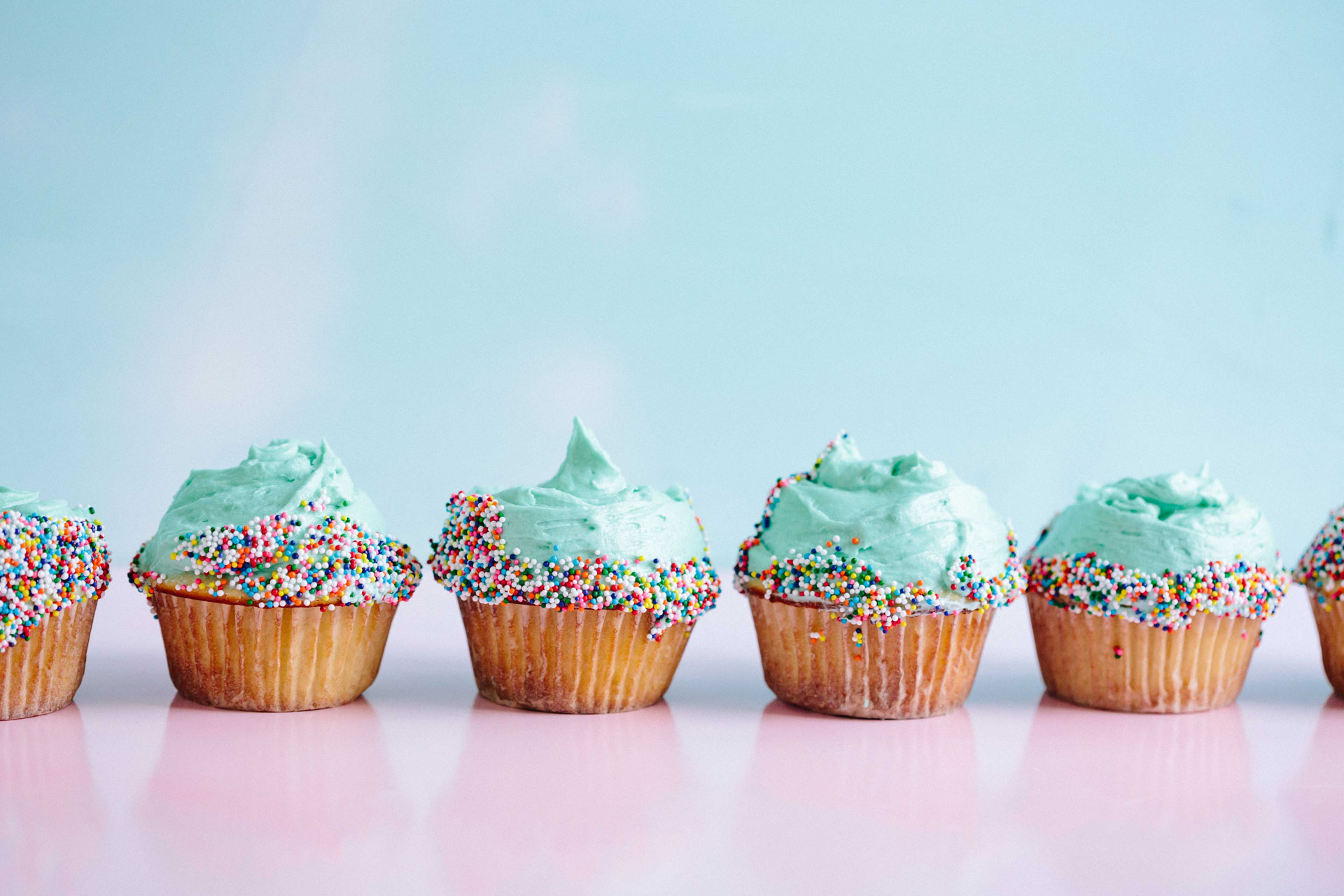 Turquoise cupcakes with sprinkles in a line