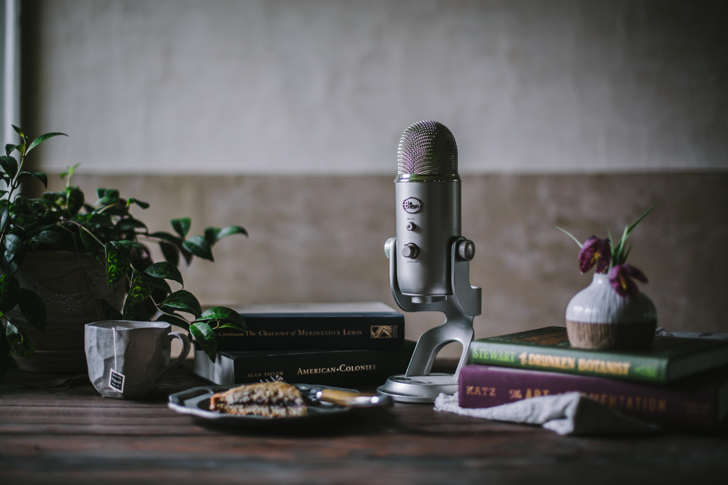 An old school microphone next to books from 'First We Eat' podcast