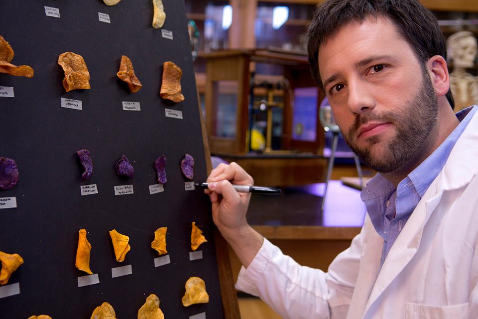 Sporkful podcaster in front of chart of colored sweet potato chips