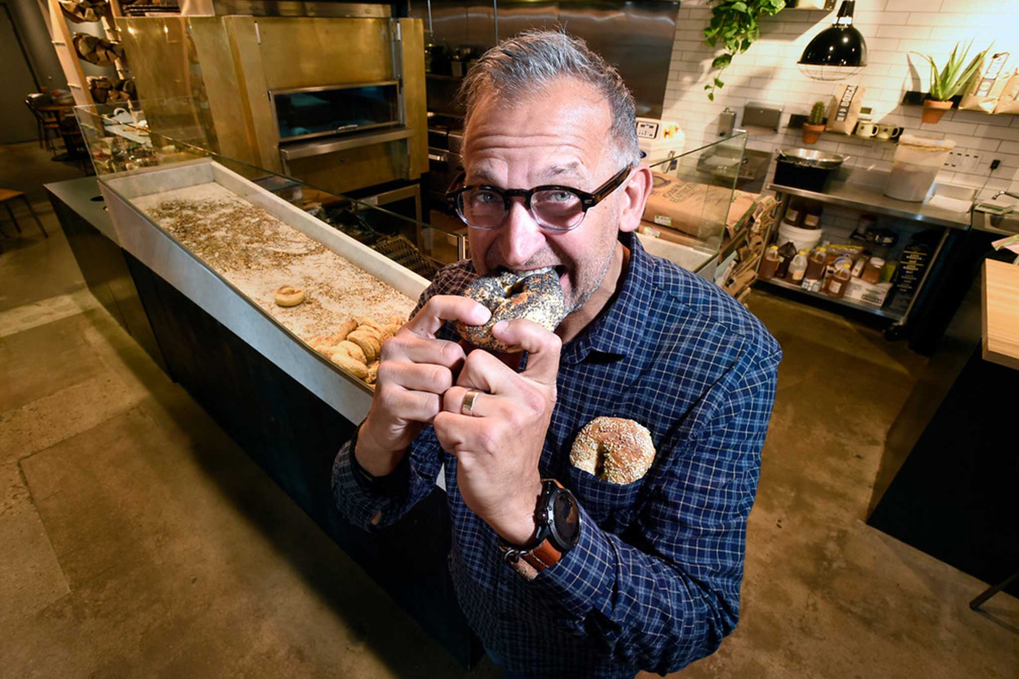 Woodgrain Bagels owner taking a bite into a bagel