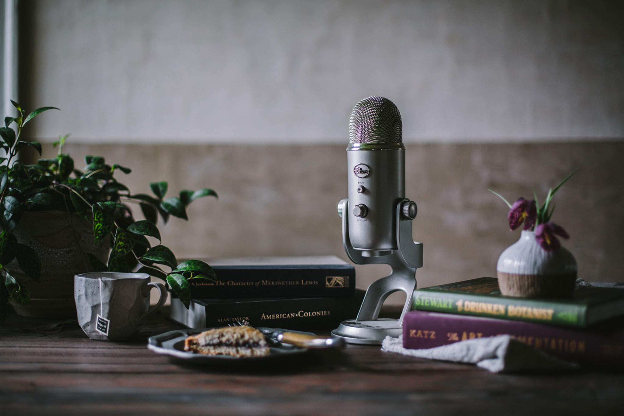 An old school microphone next to books from 'First We Eat' podcast