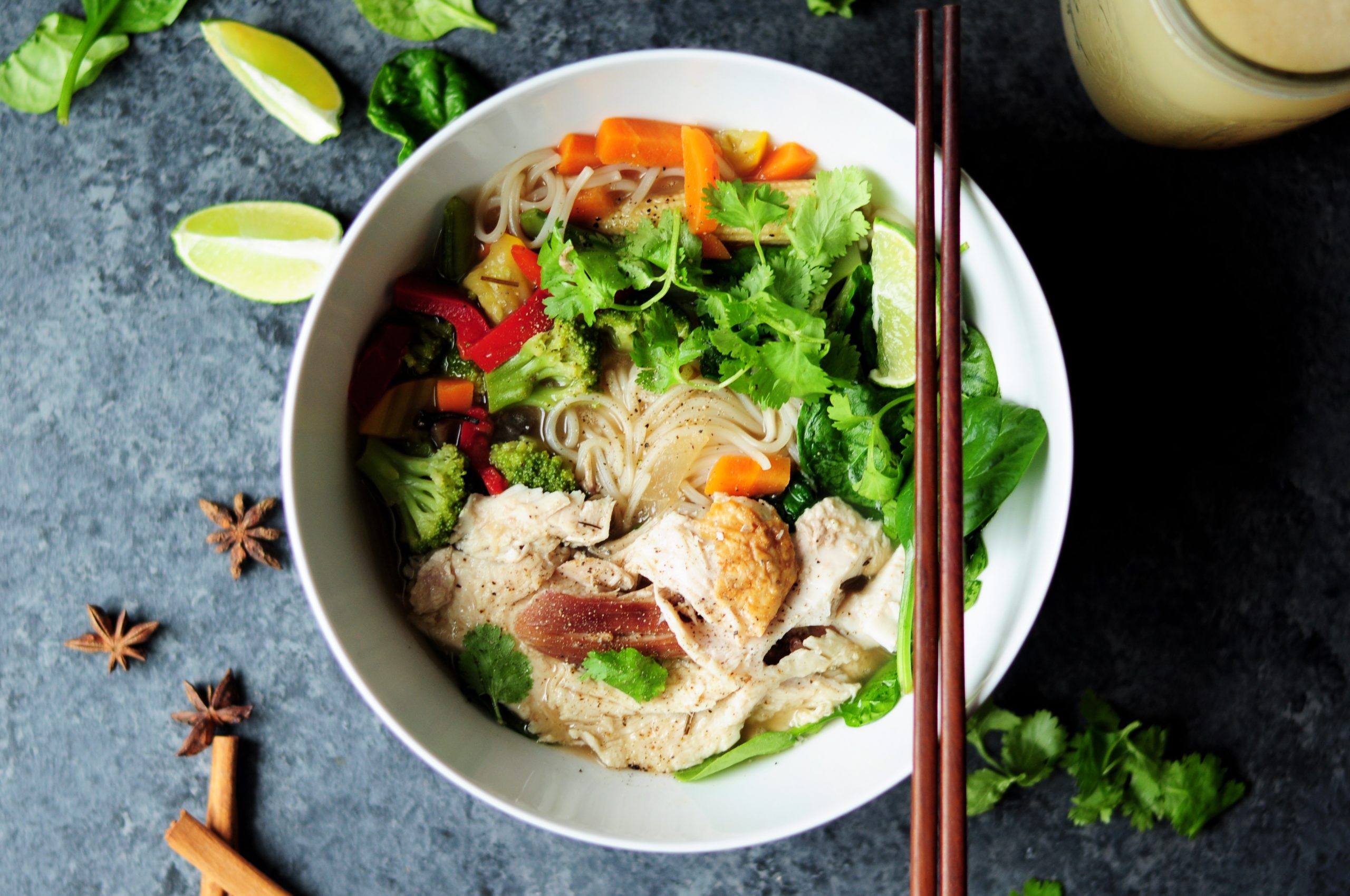Noodle soup with vegetables in a bowl with chopsticks and lime wedges