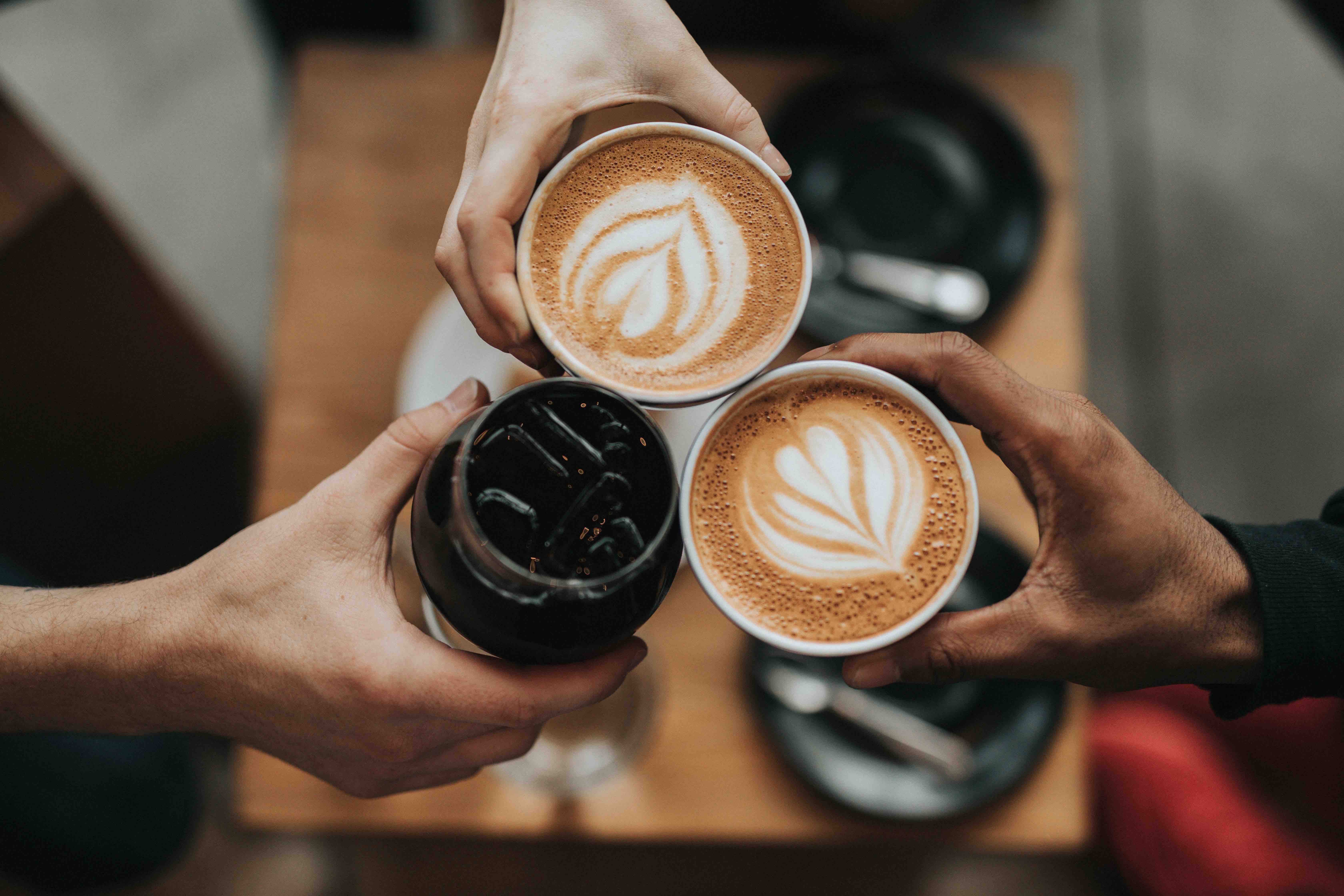 Three hands holding coffees cheers each other 