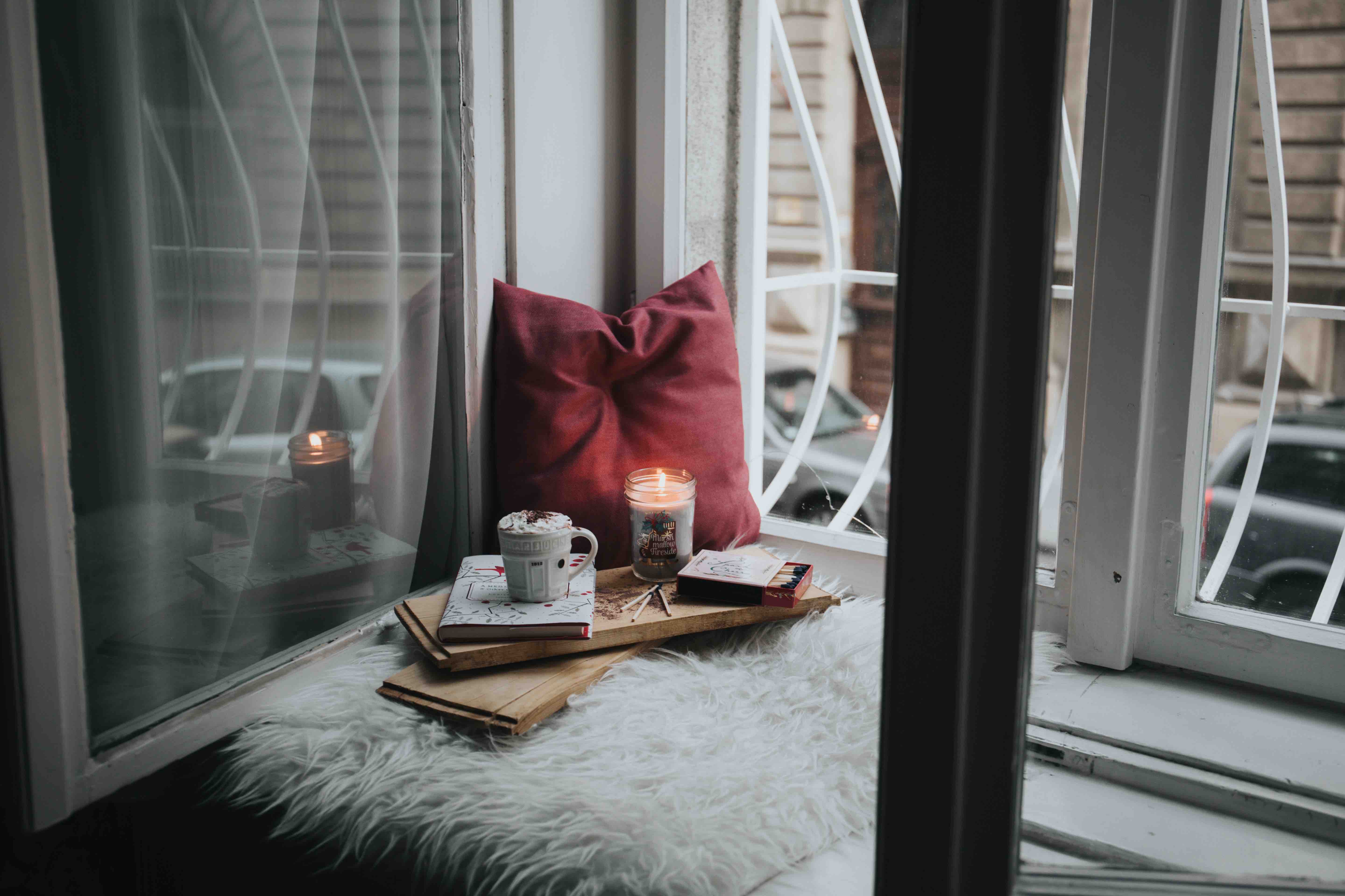 Cozy corner at home with a candle, books, and a pillow