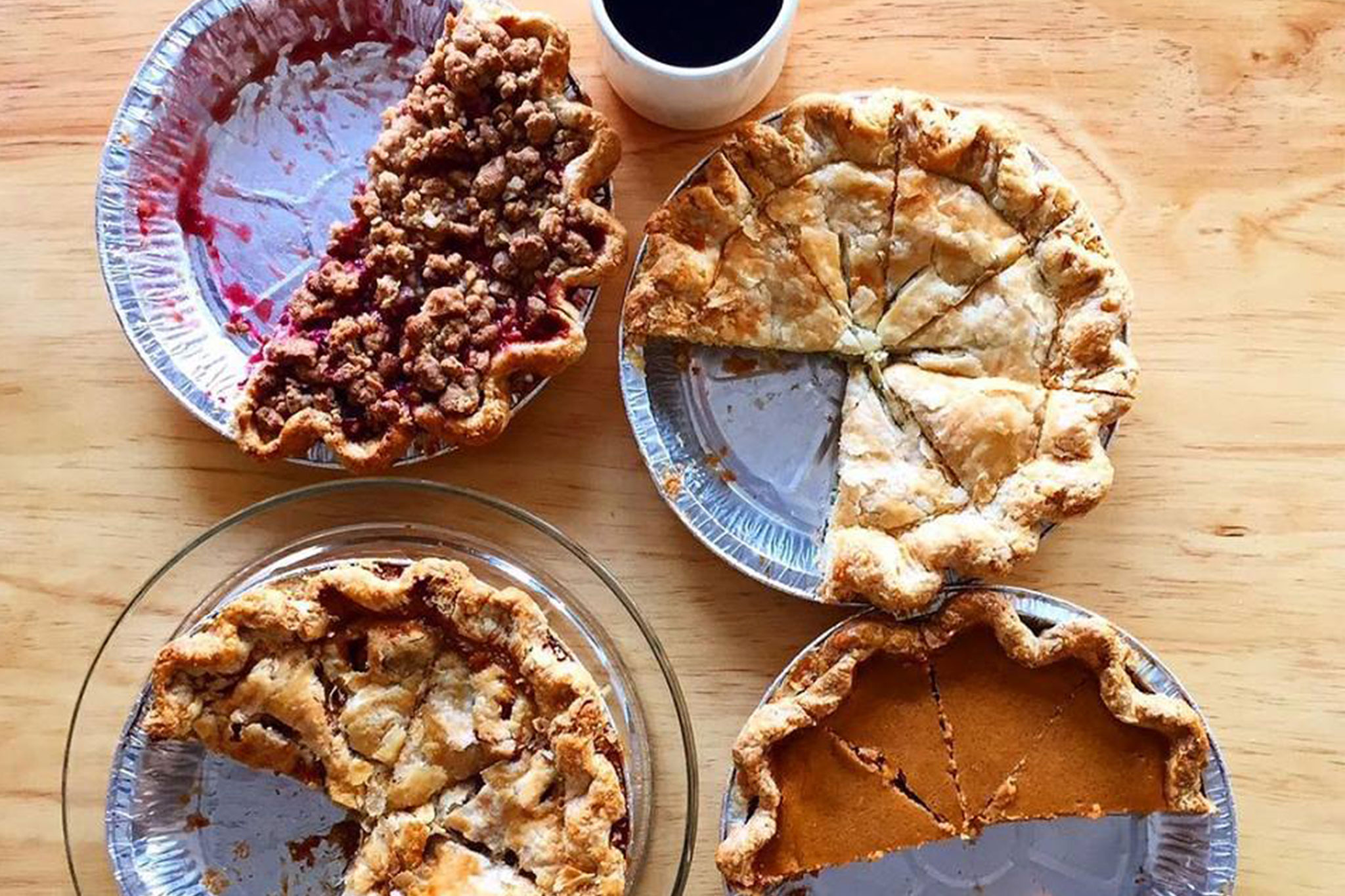 Four different kinds of pies with pieces missing from each