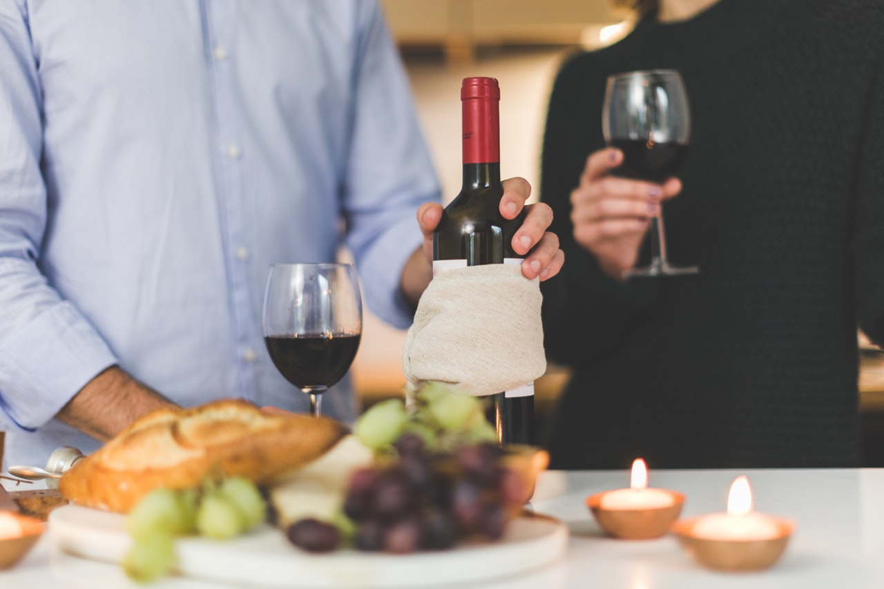 Two men holding glasses of red wine with charcuterie in front of them