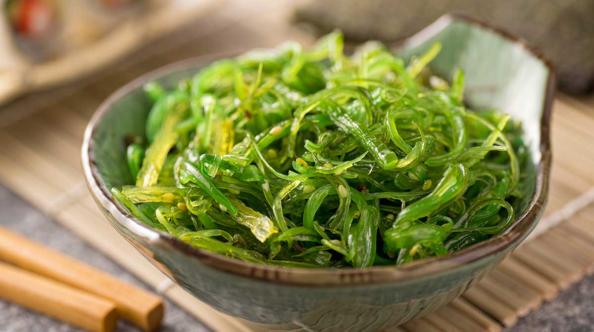 Seaweed salad in a bowl with chopsticks