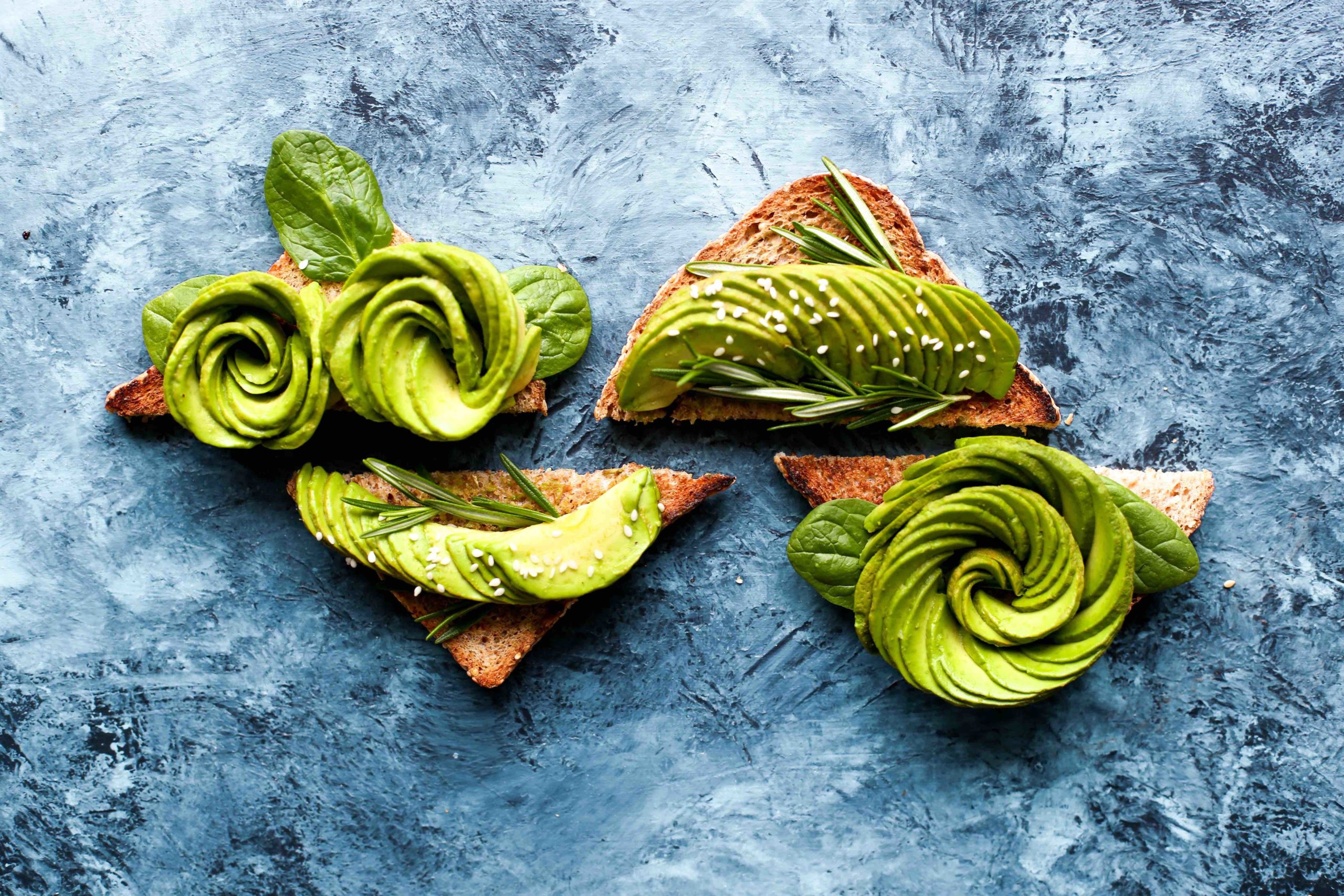 Swirls of avocado on toast slices on a stone background