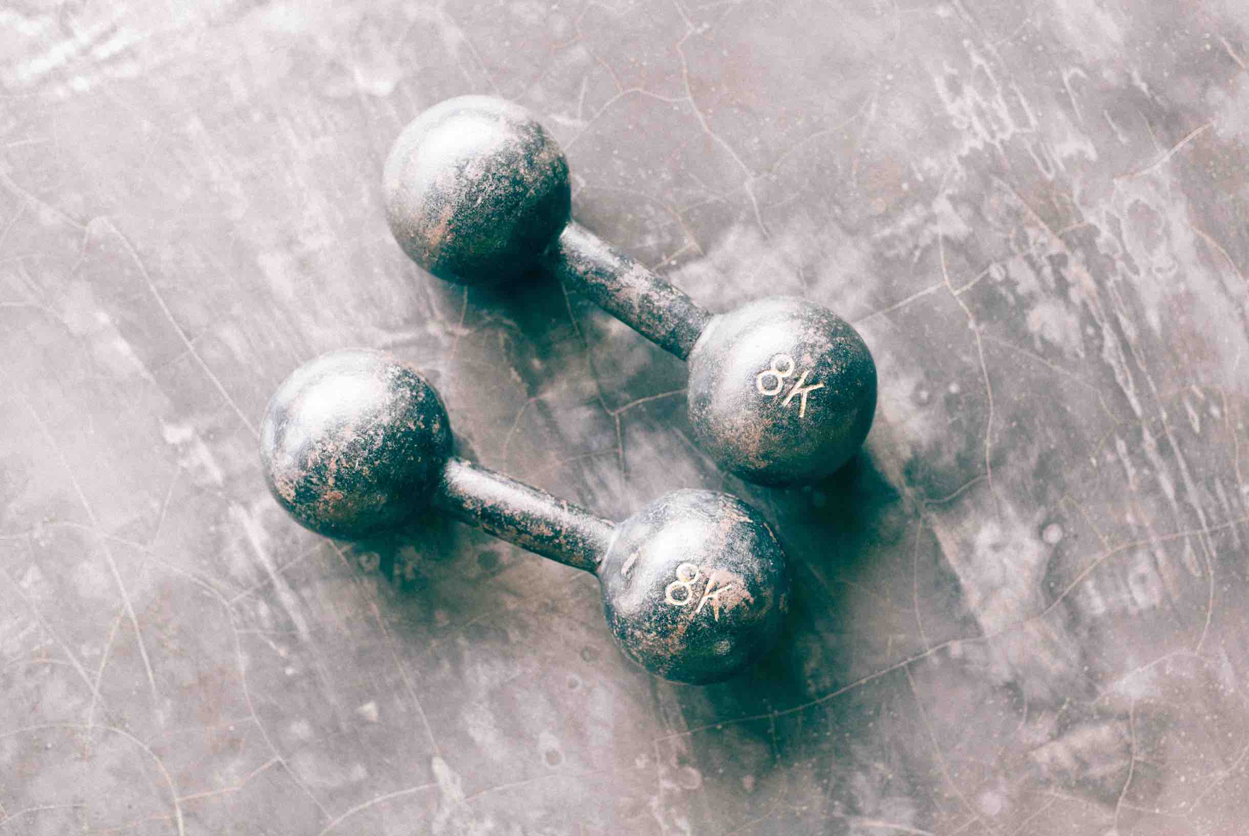 Two 8K dumbbell weights on concrete