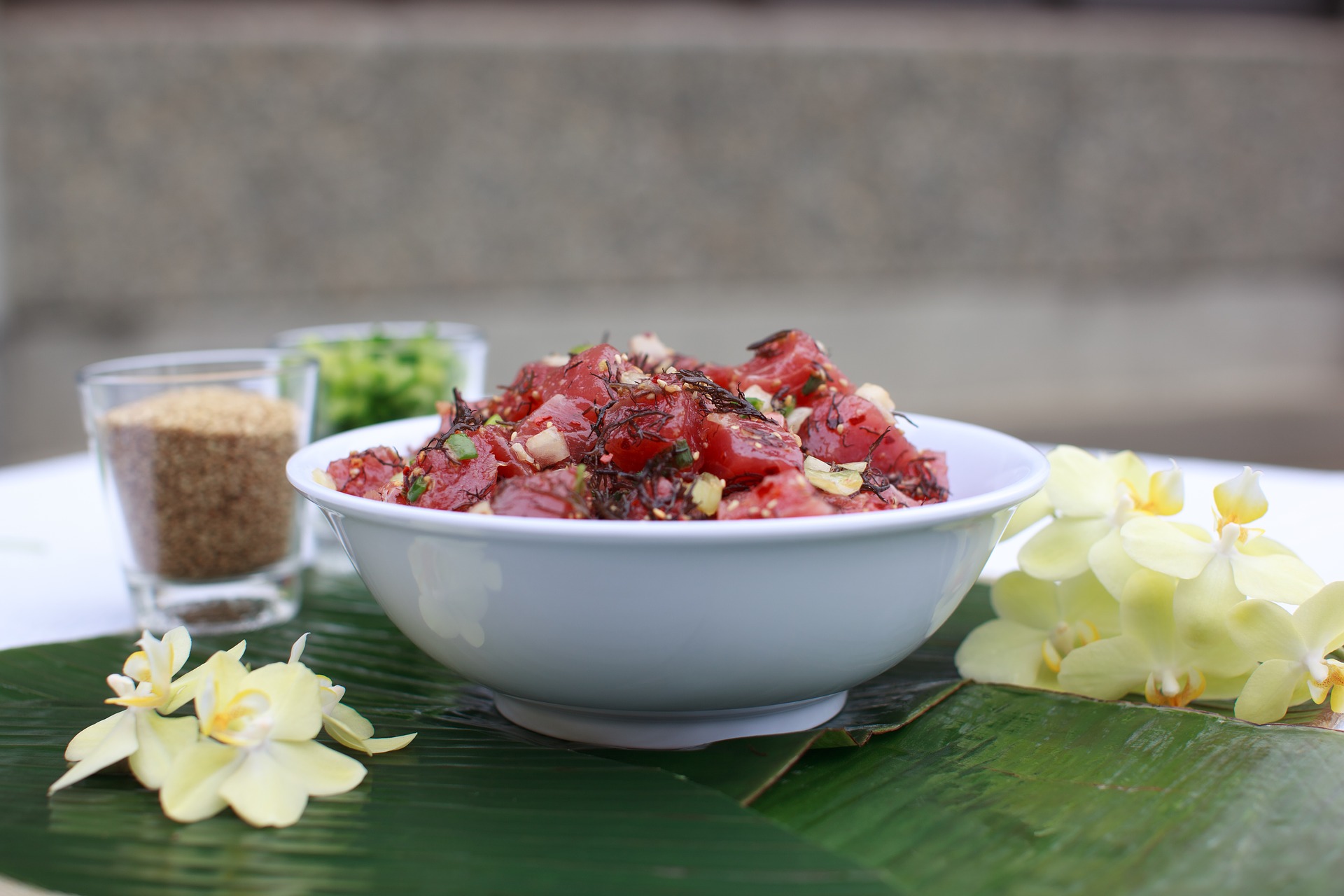 A poke bowl on banana leaves with tropical flowers