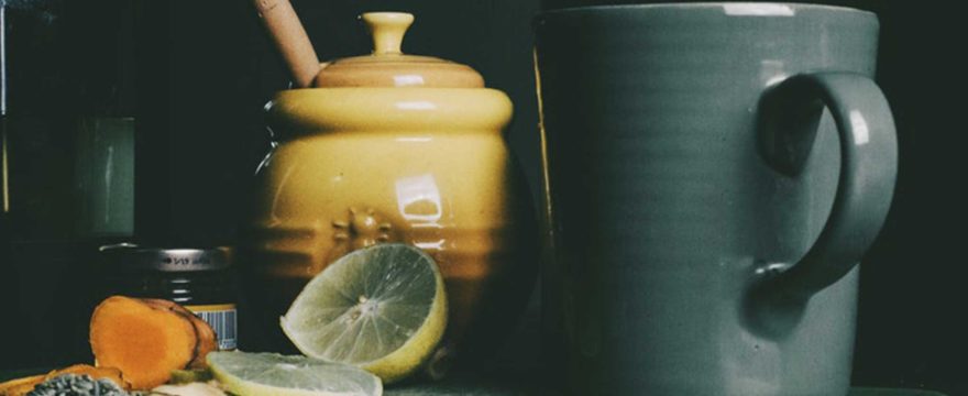 Honey pot, mug, lemon and turmeric slices on a cutting board