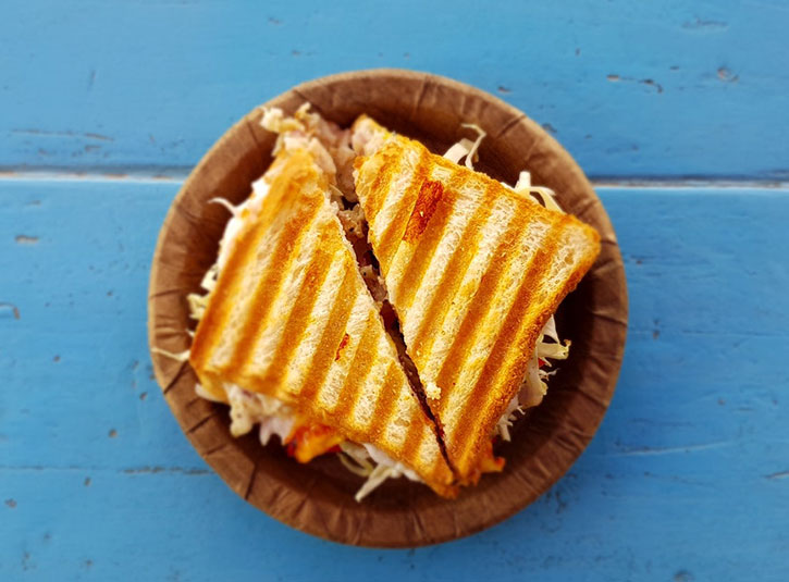 Sliced grilled sandwich on a plate on a blue table