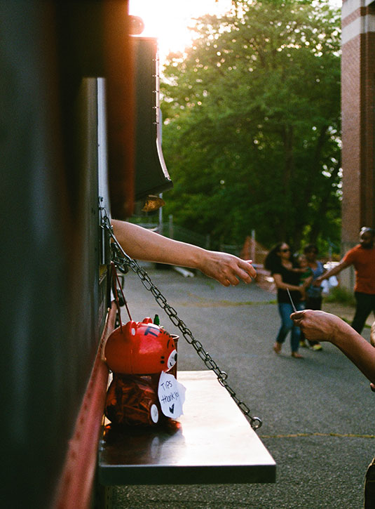 Hands passing a card to someone out of an open food truck window 