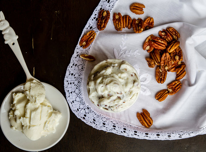Two small bowls of ice cream with pecans on a lace napkin