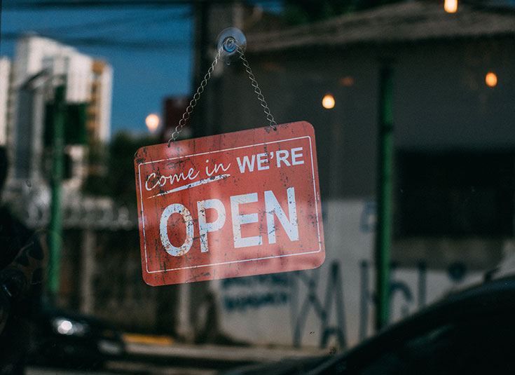 A 'come in we're open' sign hanging in a window