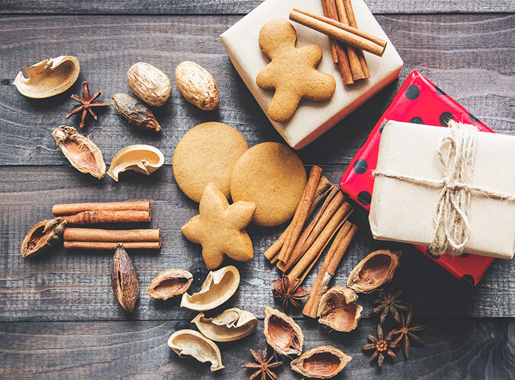 Ginger cookies, holiday spices, and little wrapped presents on a wood table