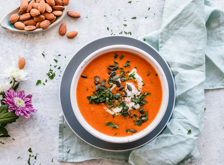 Tomato soup topped with herbs, seeds, and yogurt with almonds on the side