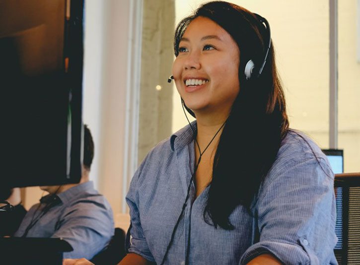 A customer service person smiles as she speaks into her headset