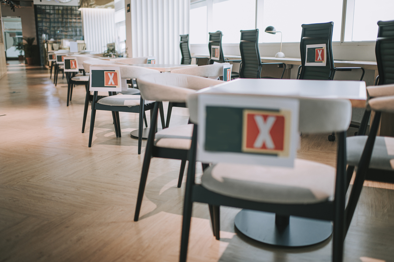 Social distancing in co-sharing office with X signs on chairs to avoid sitting in