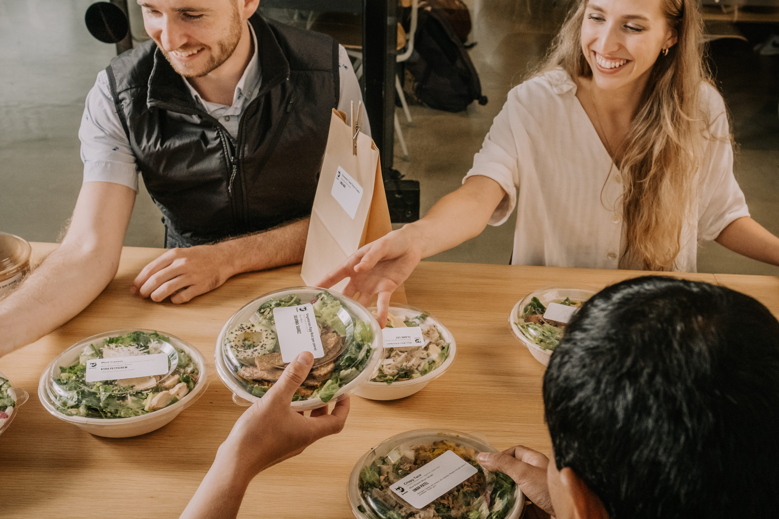 Employees smiling as they get their office lunch in to-go containers