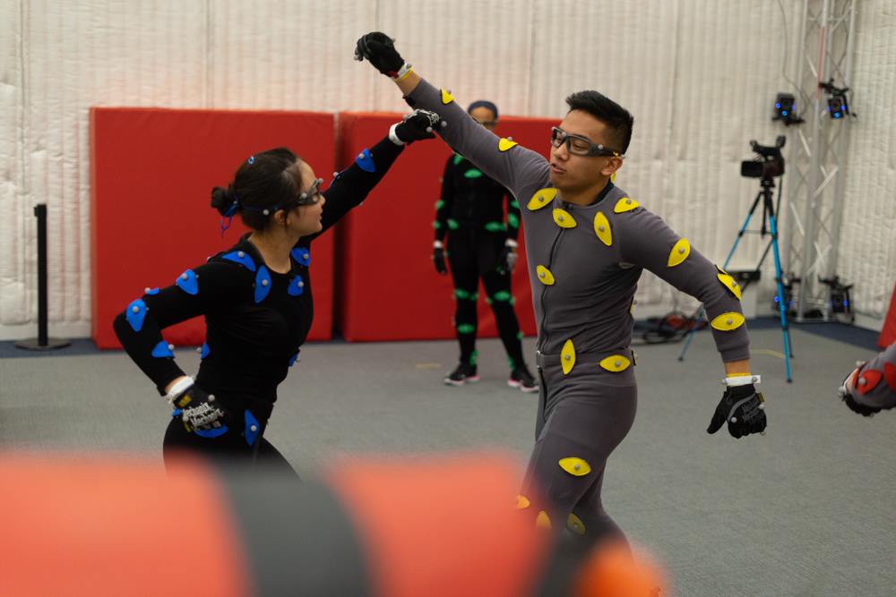 Two actors wearing body suits with nodes to outline their bodies while filming a fight scene for a video game or movie.