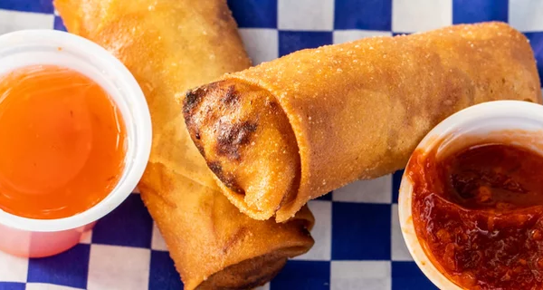 Two spring rolls with sweet and spicy dipping sauces.