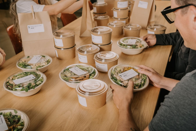 A table filled with individually packaged orders from Foodee with labels for each individual at Beyond Capture Studios.