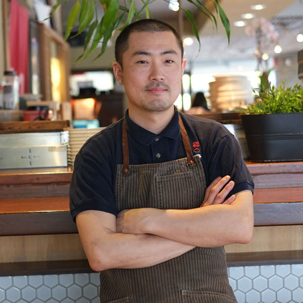 A headshot of a chef in front of their restaurant.