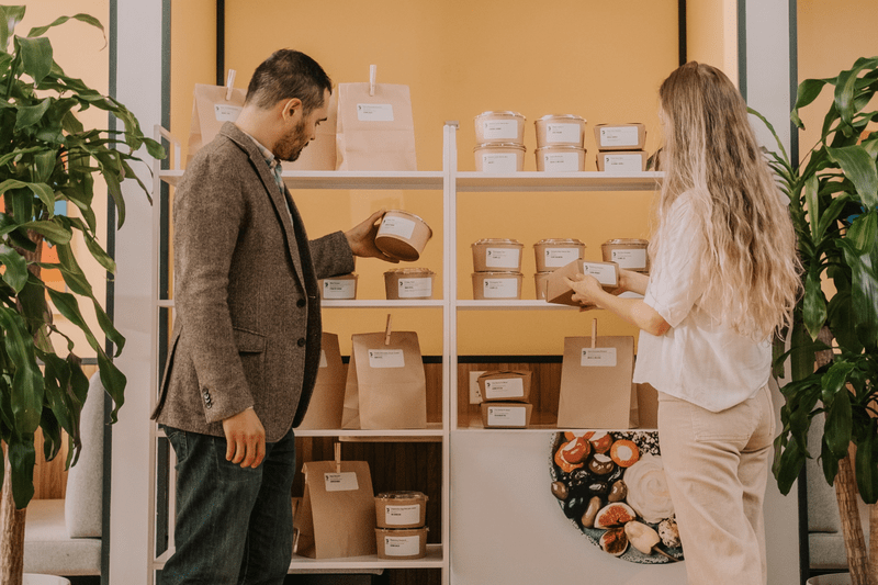 Two professionals selecting their individual pre-packaged Foodee meal from a shelf.