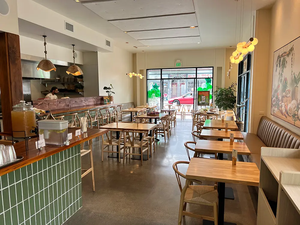 Healthyish restaurant interior with a large window with wooden tables and chairs.