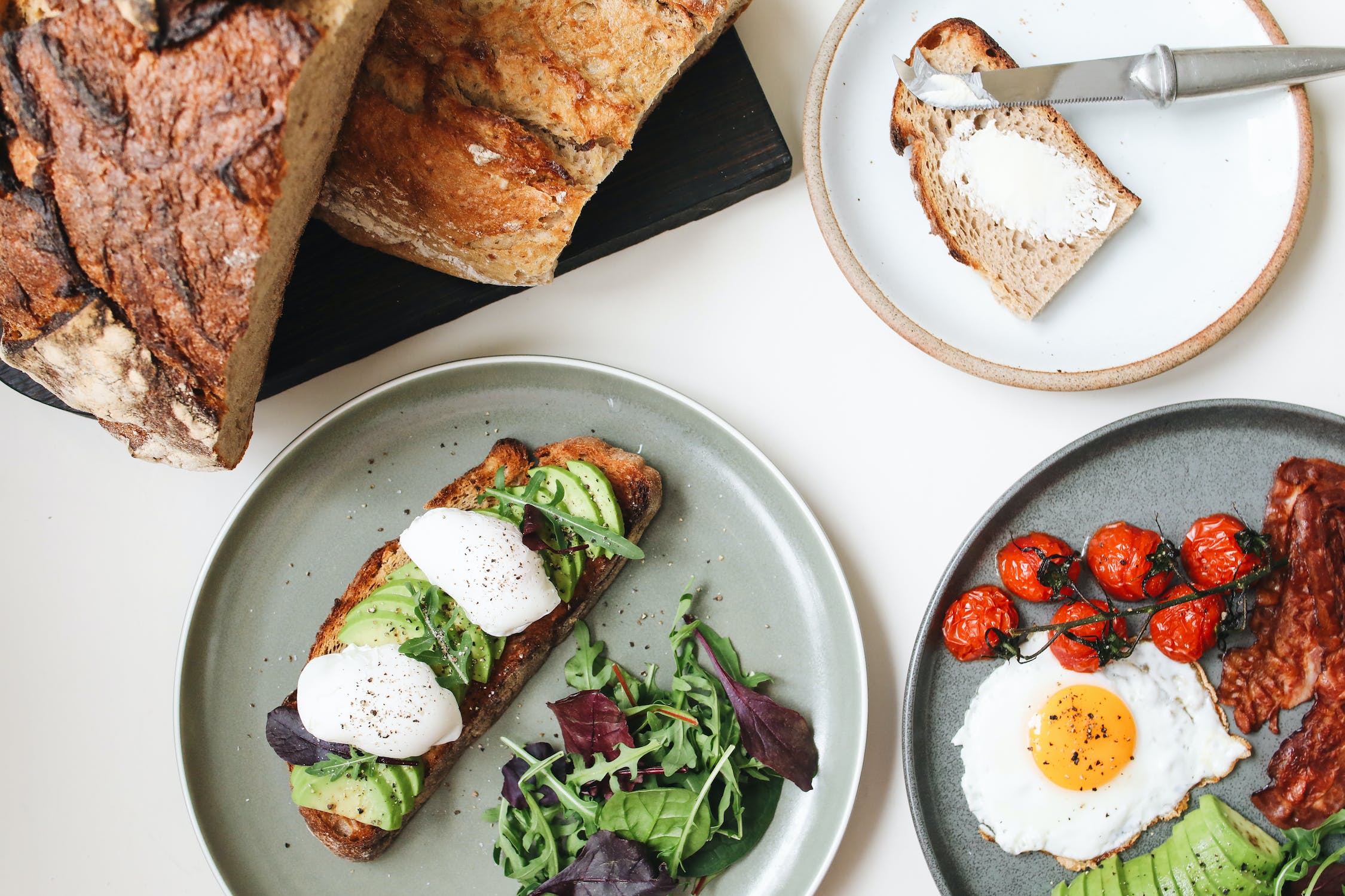 Breakfast items on plates next to sliced bread