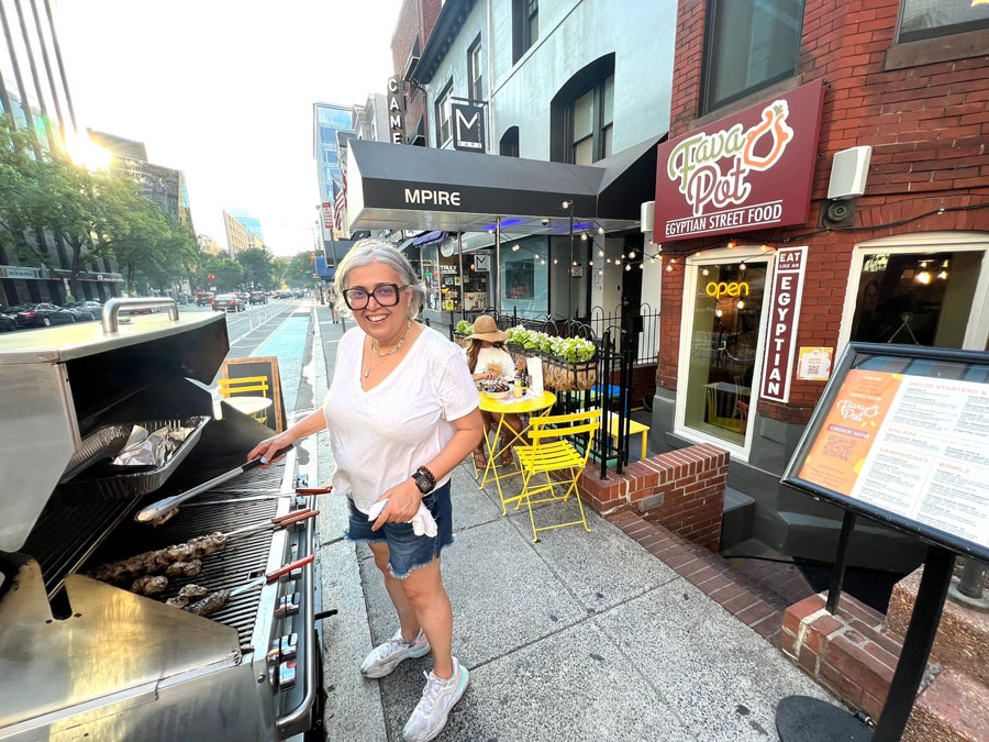 A Fava Pot chef grilling meat on top of a barbecue in front of the Fava Pot restaurant.