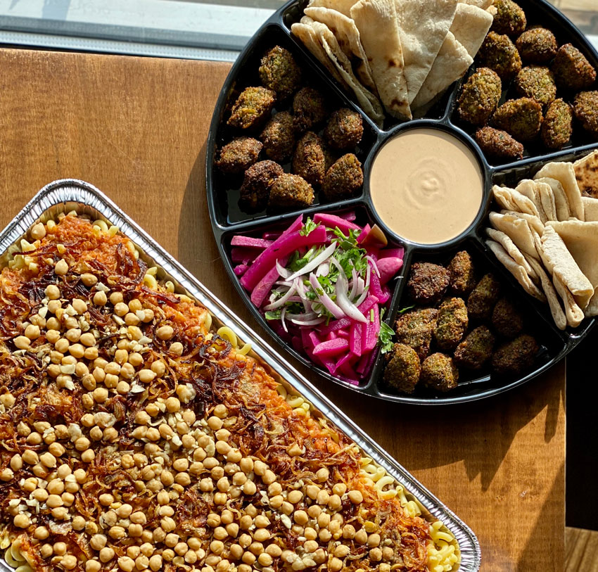 A platter of chickpeas beside an assortment of sliced pita, fallafel placed around a tahini dip.