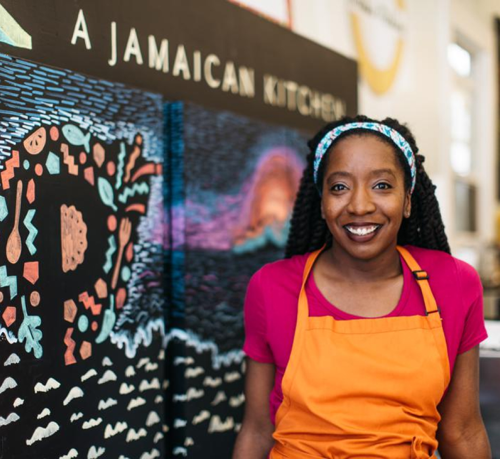 A woman standing in front of a restaurant sign.