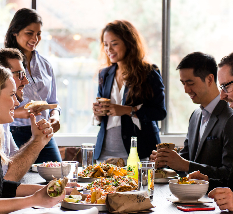 Corporate team members sitting at a table and sharing lunch together.