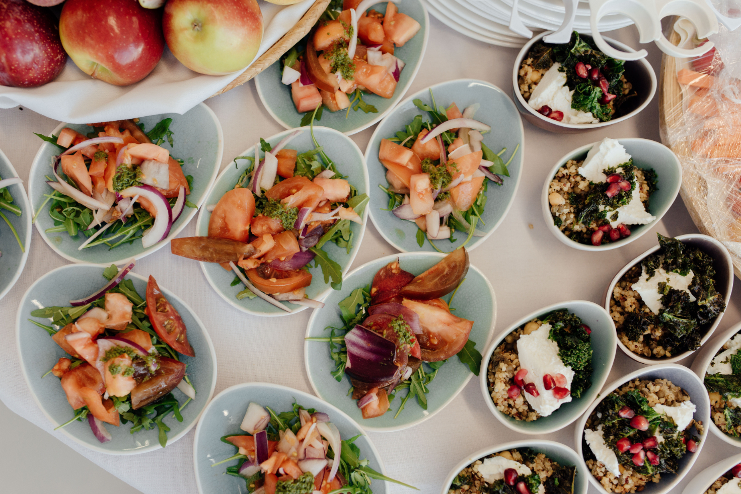 Many small dishes and a bowl of apples laid out for event catering