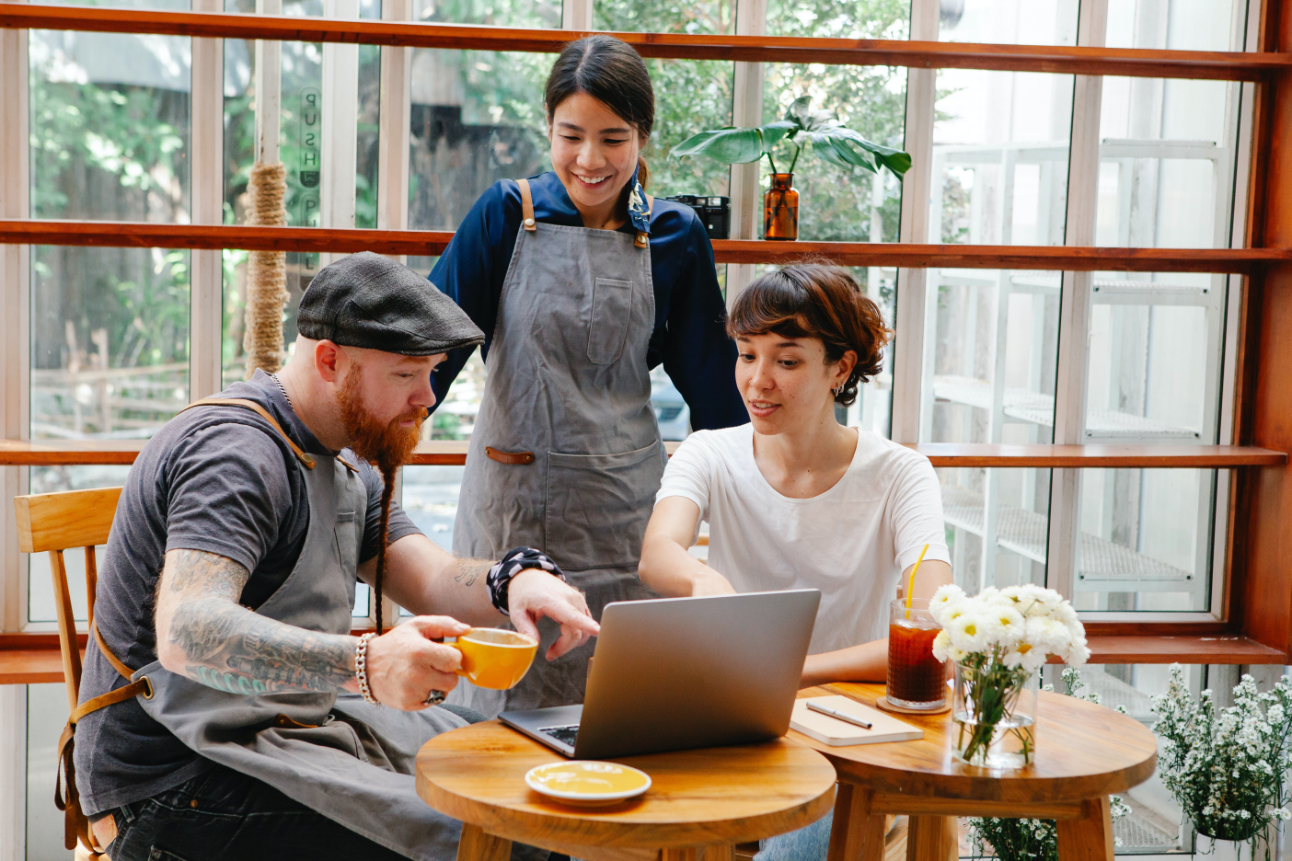 Three restaurant-industry folks looking at a laptop in a cafe