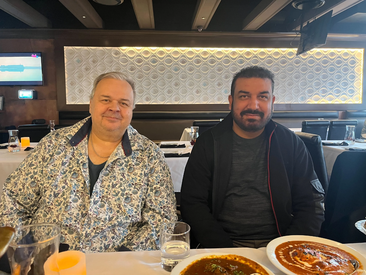 The owners of Bombay Kitchen, Sasha and Harsh, sitting at a table in their restaurant.