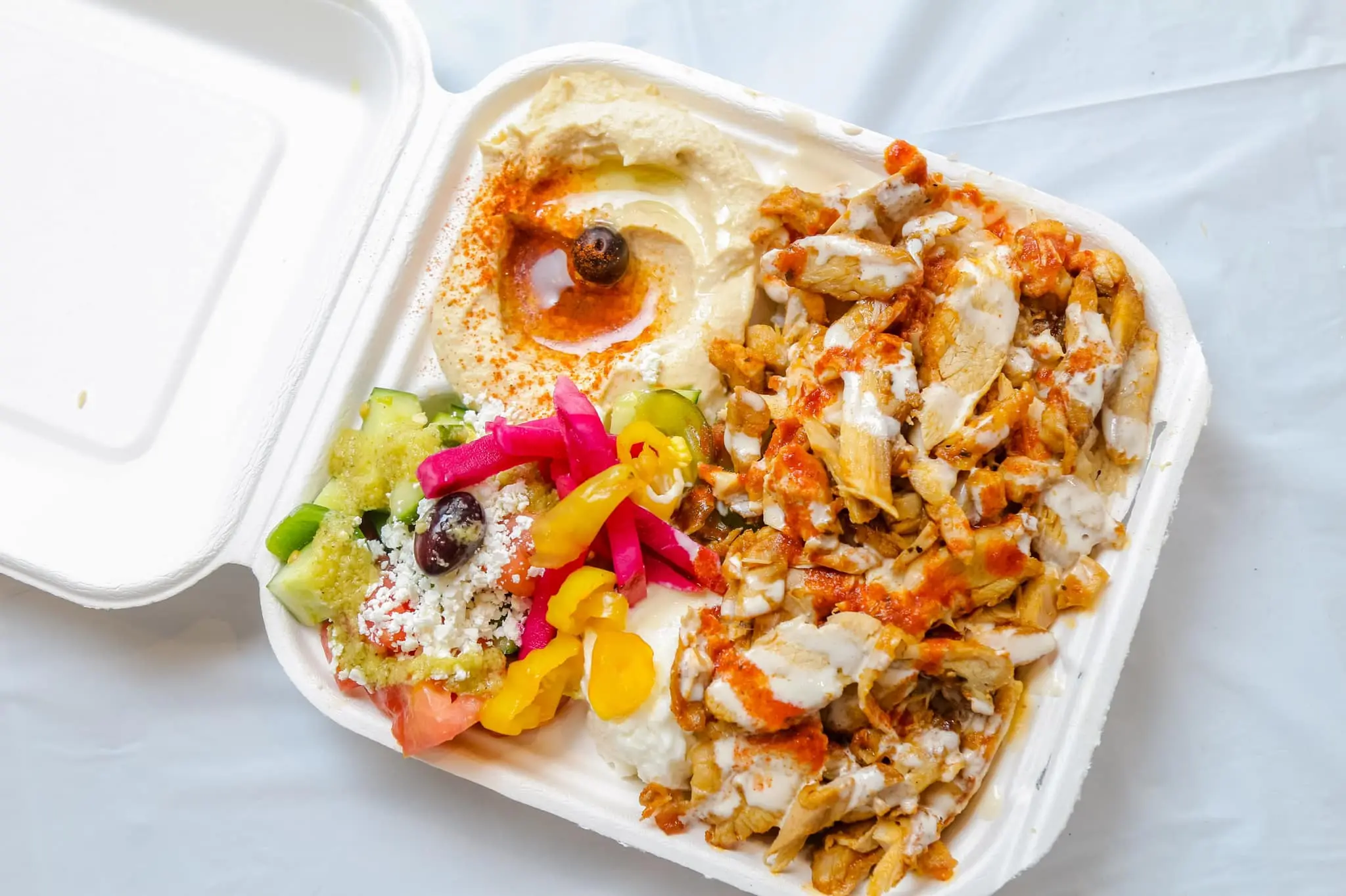 A Chicken Shawarma Plate containing chicken breast & thigh, rice, hummus, salad, and pita bread.