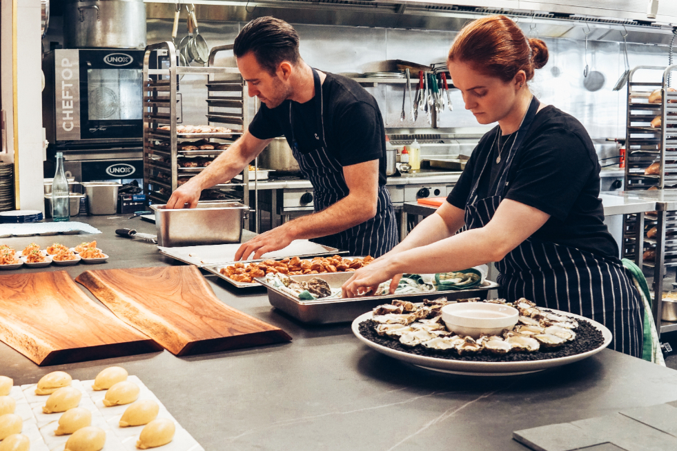 Two caterers assembling appetizers on to platters