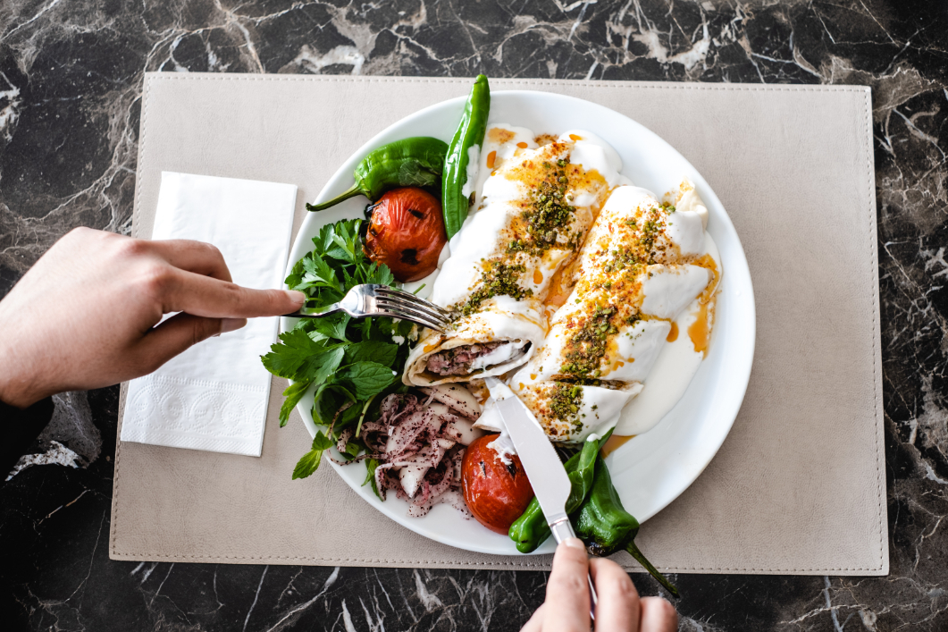 Hands holding a fork and knife to into their meal 