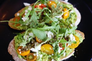 Arugula, sliced cherry tomatoes, avocado, and feta on toast