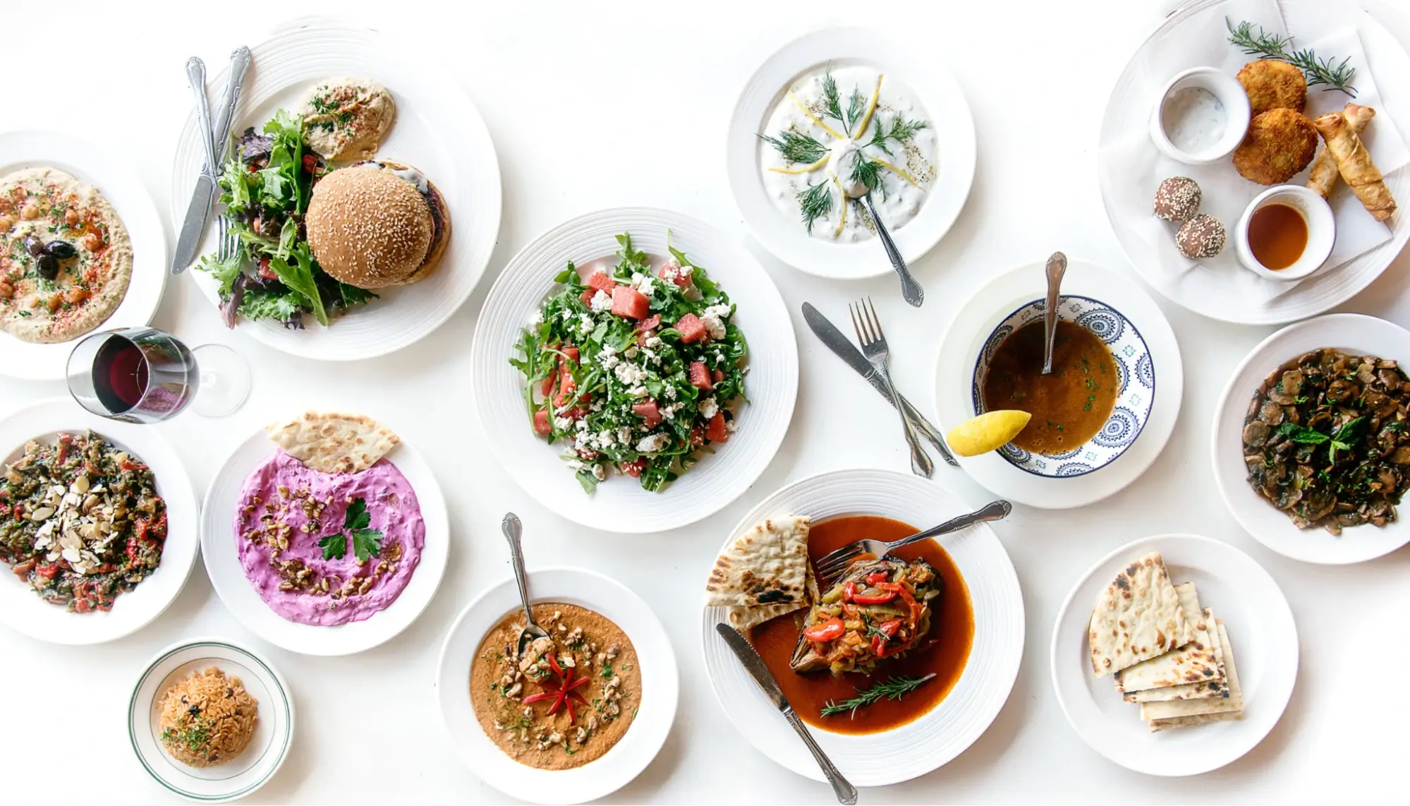 An assortment of Mediterranean meals in white dishes on a white background