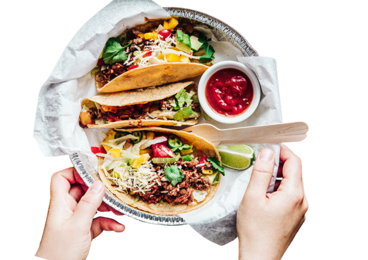 A plate of three soft shell tacos with meat, cheese, bell peppers and cilantro, with a side of hot sauce.